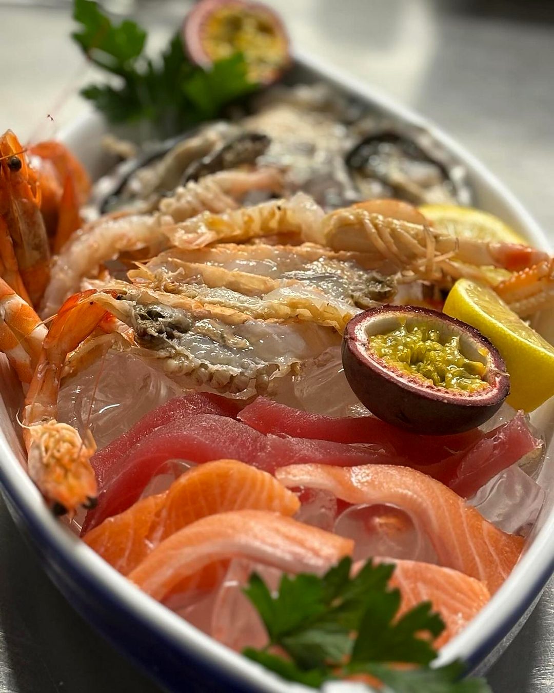 Rohe Meeresfrüchte auf Eis: Gamberi, Austern, Thunfisch, Lachs und Passionsfrucht