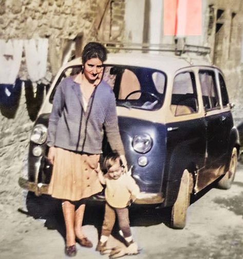 Eine Mutter mit ihrem Kind vor einem alten Fiat